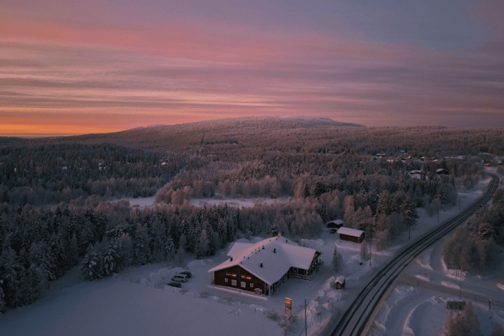 Aerial view of a winter road through snowy Lapland forest at dusk