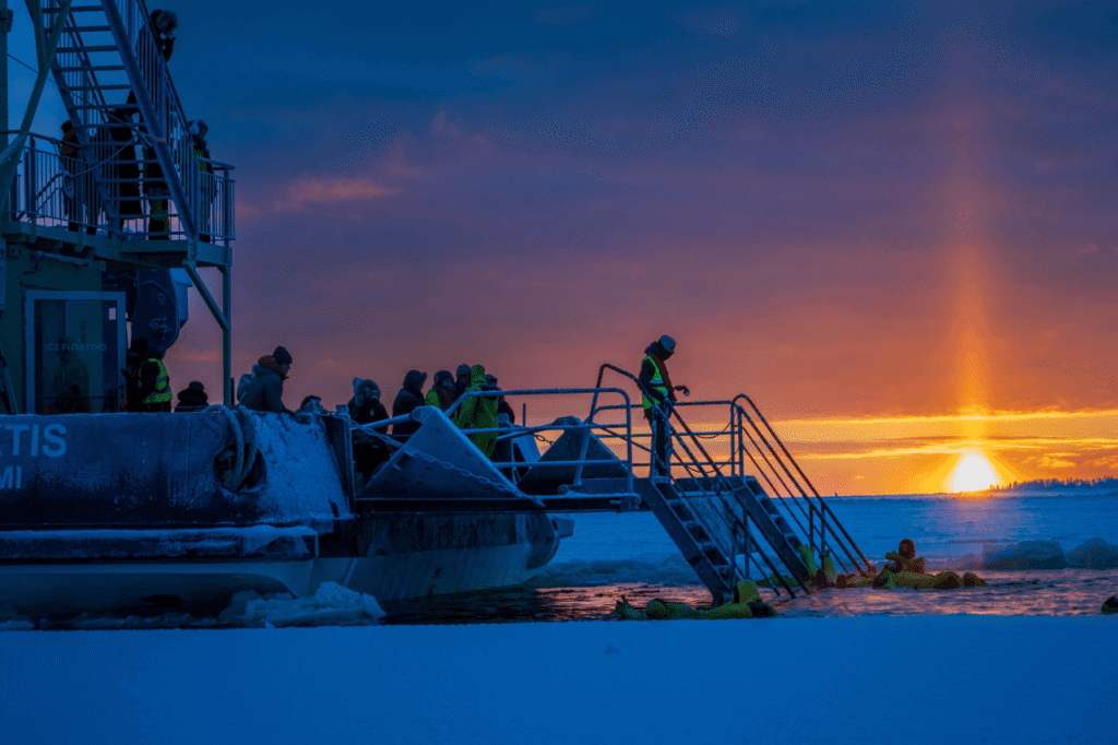 Passengers on the icebreaker deck watching the sunset over the frozen sea