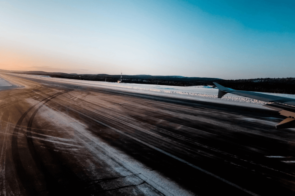 Plane landing on a winter runway at Rovaniemi Airport at sunset