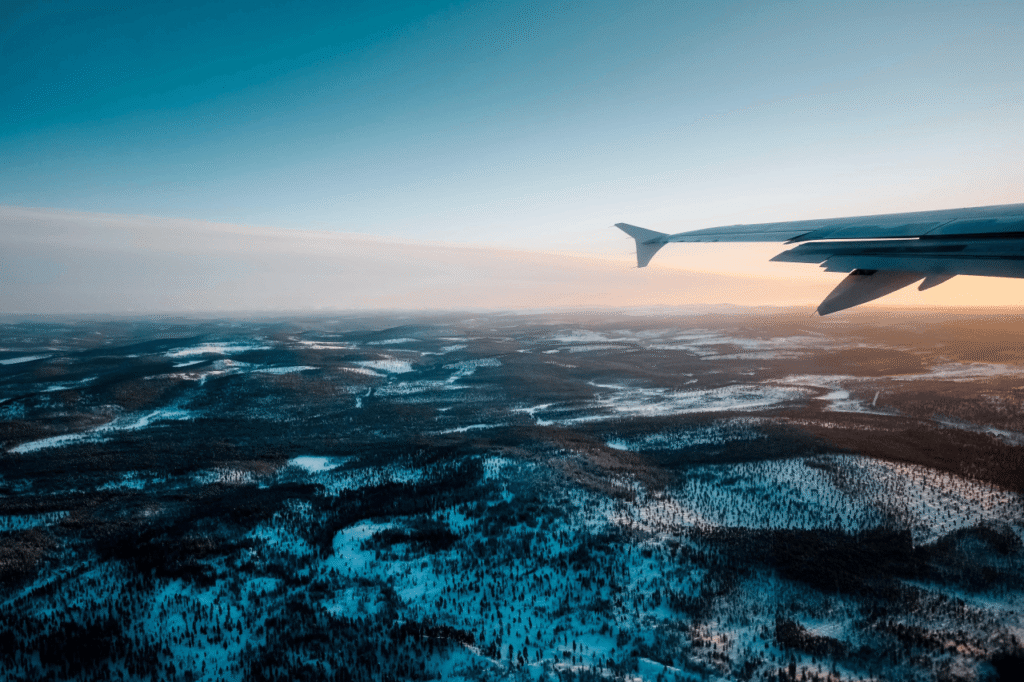 Airplane wing over snow covered Lapland landscape on approach to Rovaniemi