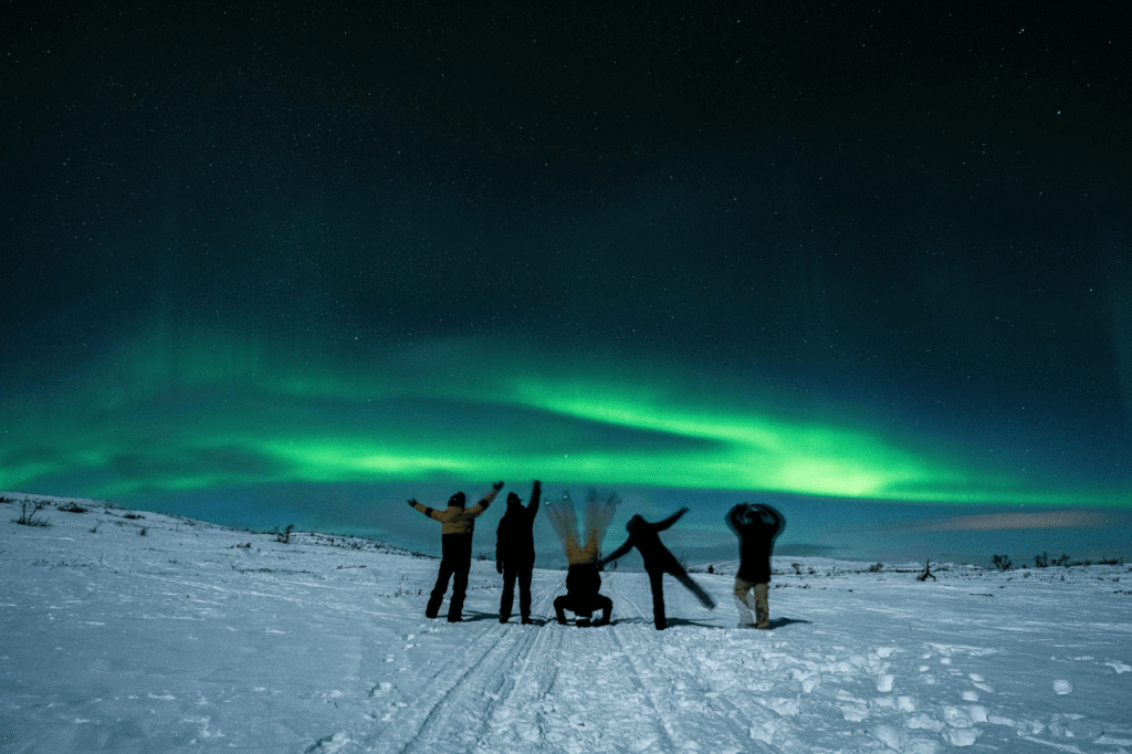 Tour group enjoying the northern lights on a snowy field near Rovaniemi